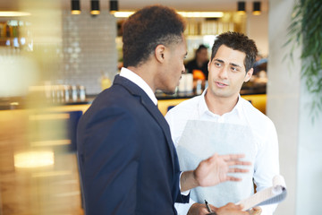Young restaurant manager gives instructions to the waiter in the restaurant