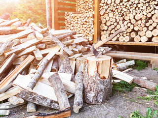 Punctured firewood in a pile, an ax in a stump against the background of a wood-burning barn