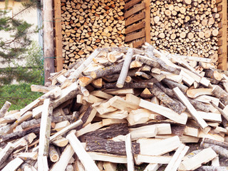 Punctured firewood in a pile against the background of a wood-burning barn