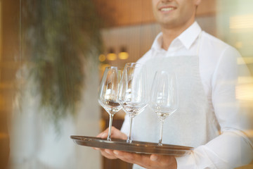 A waiter or bartender, or servant holding a tray with empty wineglasses