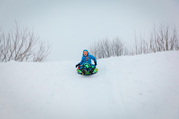 little boy enjoy winter slide, play in nature