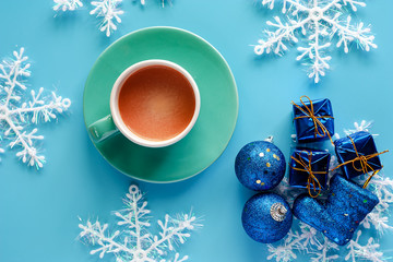 Cup of coffee with Xmas snowflake, gift box, glitter balls and boot ornaments on blue background for drinks and beverage on Christmas day and holidays concept