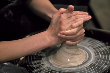 The hands of the master working with clay on a potter's wheel, close-up