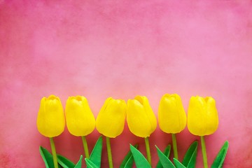Artificial yellow tulips on pink background for nature decoration and springtime concept