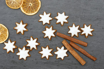 cinnamon star, cinnamon sticks and orangen slices lying on black slate