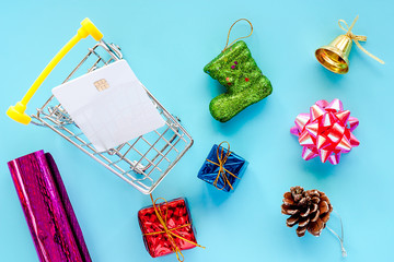 Xmas ornaments with blank credit chip card and mini shopping cart on blue background for Christmas day and holidays concept