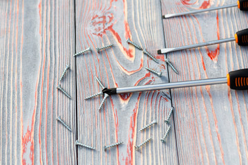 three screwdriver or one with screws in the shape of a circle. On a wooden background there are...