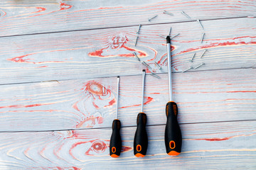 three screwdriver or one with screws in the shape of a circle. On a wooden background there are...