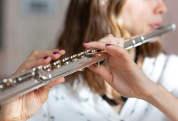Girl plays on flute. Flute in hands of girl during the concert. Professional musician playing on...
