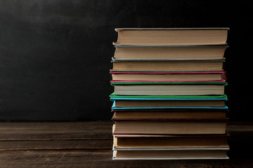 A stack of books on a brown wooden table and on a black background. Old books. Education. school. study With space for inscriptions