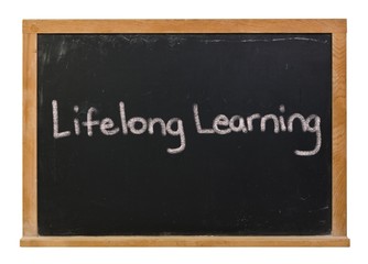 Lifelong learning written in white chalk on a black chalkboard isolated on white