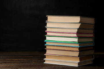 A stack of books on a brown wooden table and on a black background. Old books. Education. school. study With space for inscriptions