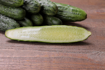 Fresh green cucumbers and cucumber in a cut on a brown wooden table. vegetables