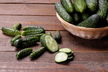 Fresh green cucumbers in a basket and slices of cucumbers on a brown wooden table. vegetables