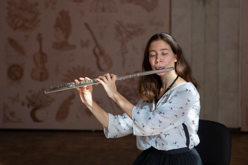 A gorgeous young woman sitting and playing the flute