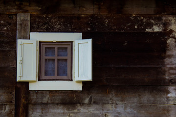 Small window with open shutters on mountain wooden house. Copy space