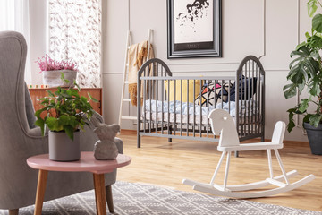White rocking horse in the middle of stylish baby room interior in grey, real photo