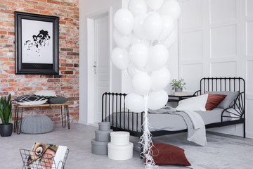 Stylish bedroom interior with grey bedding and bunch of white balloons, real photo