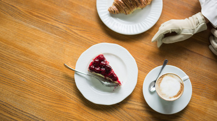 Croissant with cake with berries, chocolate spread and with cup of coffee on a marble texture background