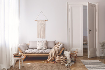 Bright living room interior with unique, handmade baskets made of natural materials and a cozy wooden sofa with beige cushions
