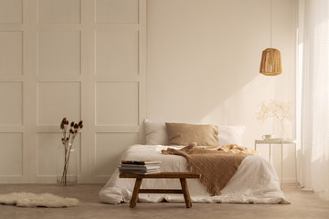 Beige blanket on the double bed in stylish wabi sabi bedroom of minimal style house, real photo...
