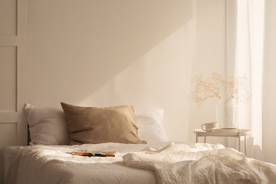 Linen sheets ion king size bed in minimal bedroom interior of stylish house, real photo with copy space on the empty wall