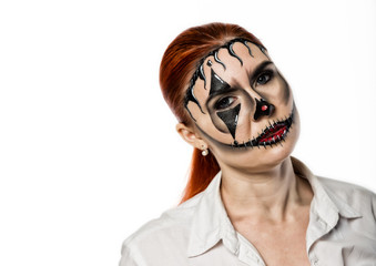 beautiful girl with terrible mask painted on her face. Halloween and creative make-up.