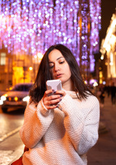 Girl with a phone on the street of the evening city