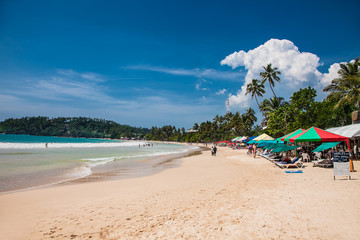 Tourists walking on the sand beach of Mirissa . Sri Lanka.
