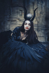 Pretty demon girl with black wings behind her back, goddess of another world beyond, Halloween...