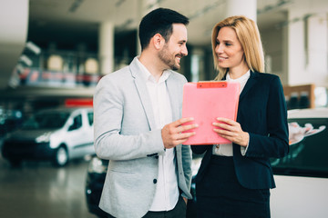 Young female car sales consultant working in showroom