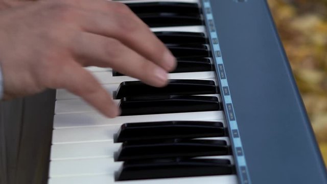 White and black synthesizer keys. The pianist's hand plays on the electronic piano