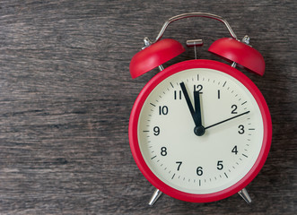 Red alarm clock on wood background.