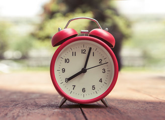Red alarm clock on a wooden table.