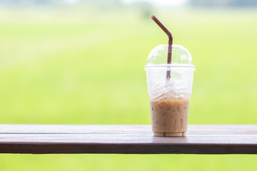 Espresso with ice cubes on the wooden table at coffee shop. Drink and feel refreshed on blur green background. Soft focus and copy space.