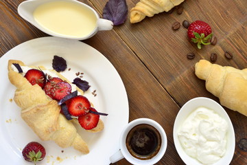 Croissant with cream cheese, strawberries and basil for breakfast, top view, copy space