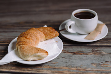 Croissant and coffee on wooden table