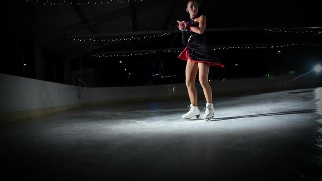 A figure skaters spins and then she elegantly finishes her performance.