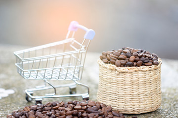 Coffee beans in brown basket with shopping cart on the table. The concept of seeds selection for beverage and distribution. Soft focus and copy space.