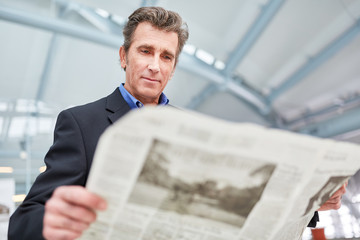 Geschäftsmann liest eine Tageszeitung im Flughafen