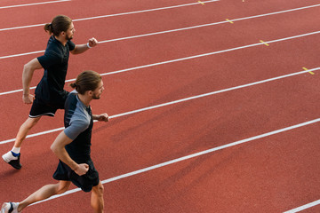 Obraz premium Two twins sportsmen brothers running at the stadium outdoors.