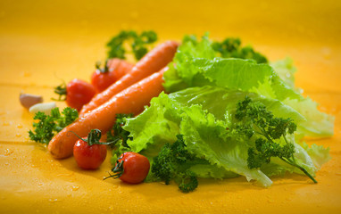 Obraz na płótnie Canvas Овощи - морковь, помидоры, чеснок, салат на желтом фоне Vegetables - carrots, tomatoes, garlic, lettuce on a yellow background