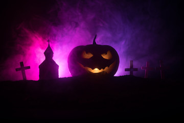 Scary view of zombies at cemetery dead tree, moon, church and spooky cloudy sky with fog, Horror Halloween concept with glowing pumpkin.