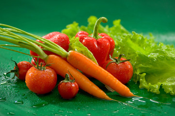 Овощи - морковь, помидоры, перец, салат, на зеленом фоне Vegetables - carrots, tomatoes, peppers, lettuce, on a green background