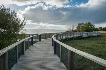 Fototapeta na wymiar Boardwalk path through coastal meadow area. Boardwalk in Parnu coastal meadow hiking trail. Estonia. Baltic.