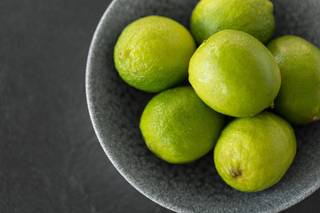 food, healthy eating and vegetarian concept - close up of whole limes in bowl