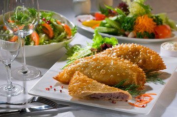 Чебуреки на белой тарелке на сервированном белом столе Chebureks on a white plate on a served white table