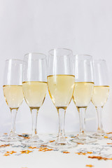 Glasses with champagne with gold and silver star shaped confetti on a light background. New year or Christmas concept. Copy space.