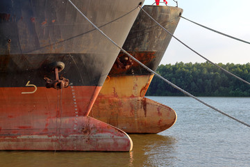 Prows of two old rusty ships with anchor chain anchored at Danube river at summer