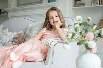 Obraz na płótnie Canvas Cheerful little girl in pink dress having fun at home